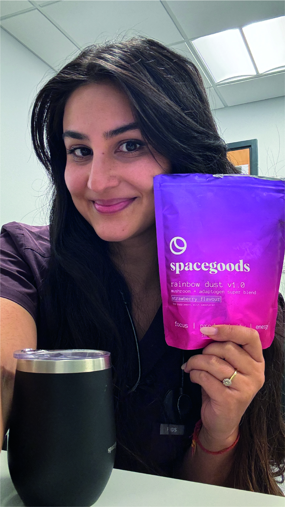 Person holding a purple and pink package labeled 'spacegoods' next to a black cup.