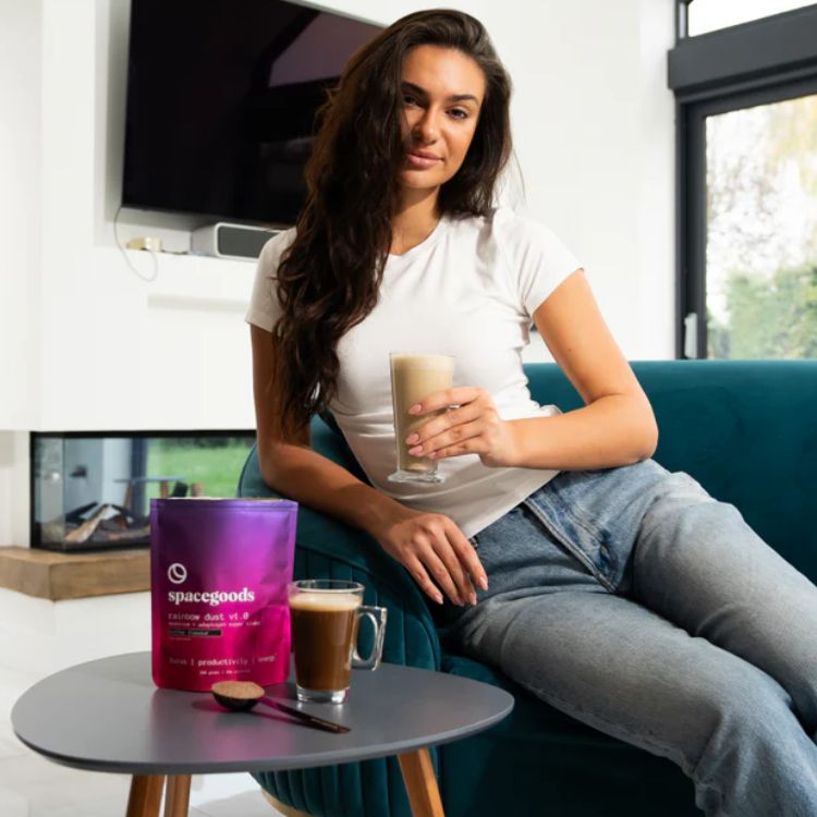Woman sitting with a drink, next to a table with coffee and product package.
