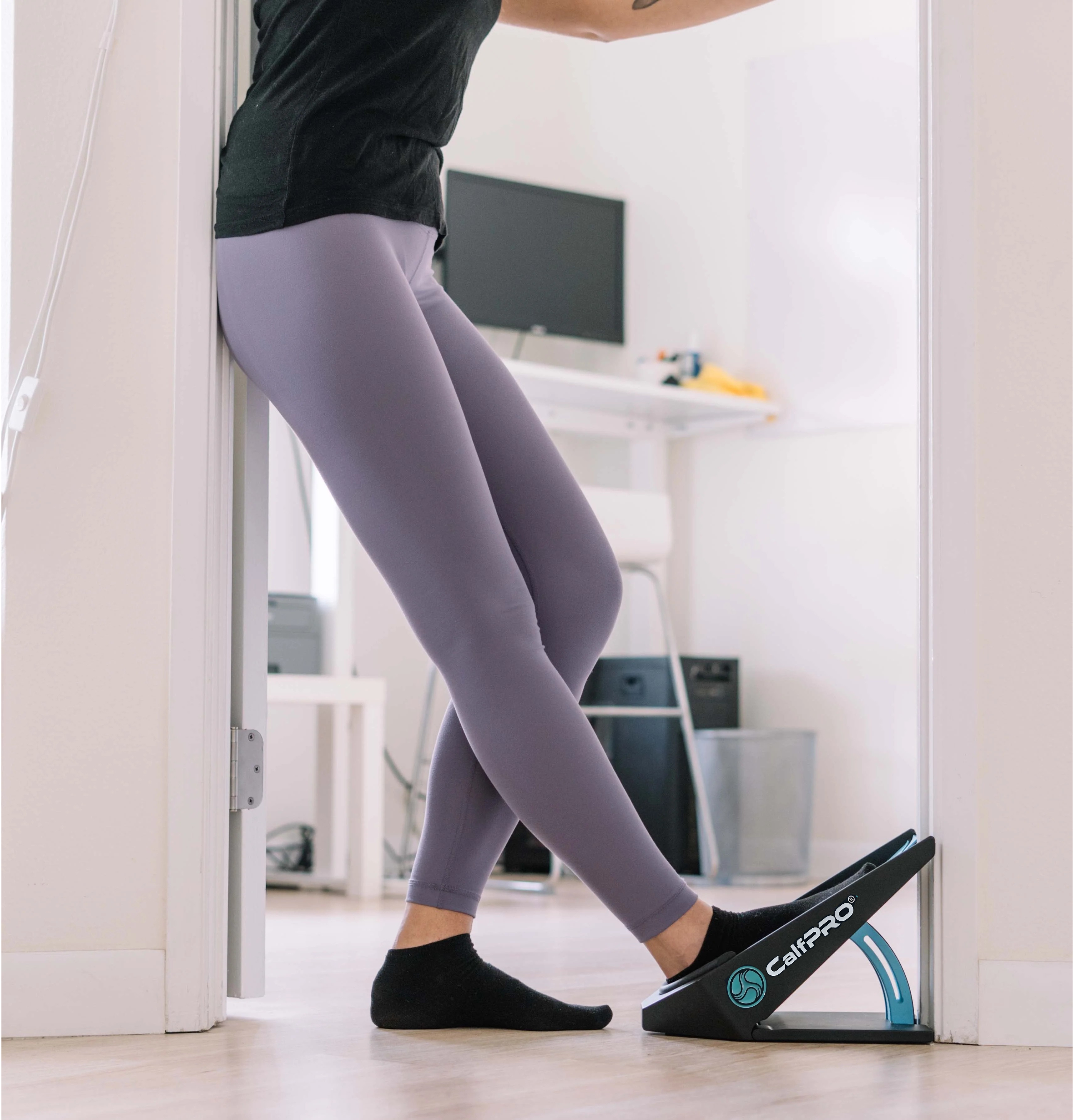 Person using a slant board for stretching in a home office setting.