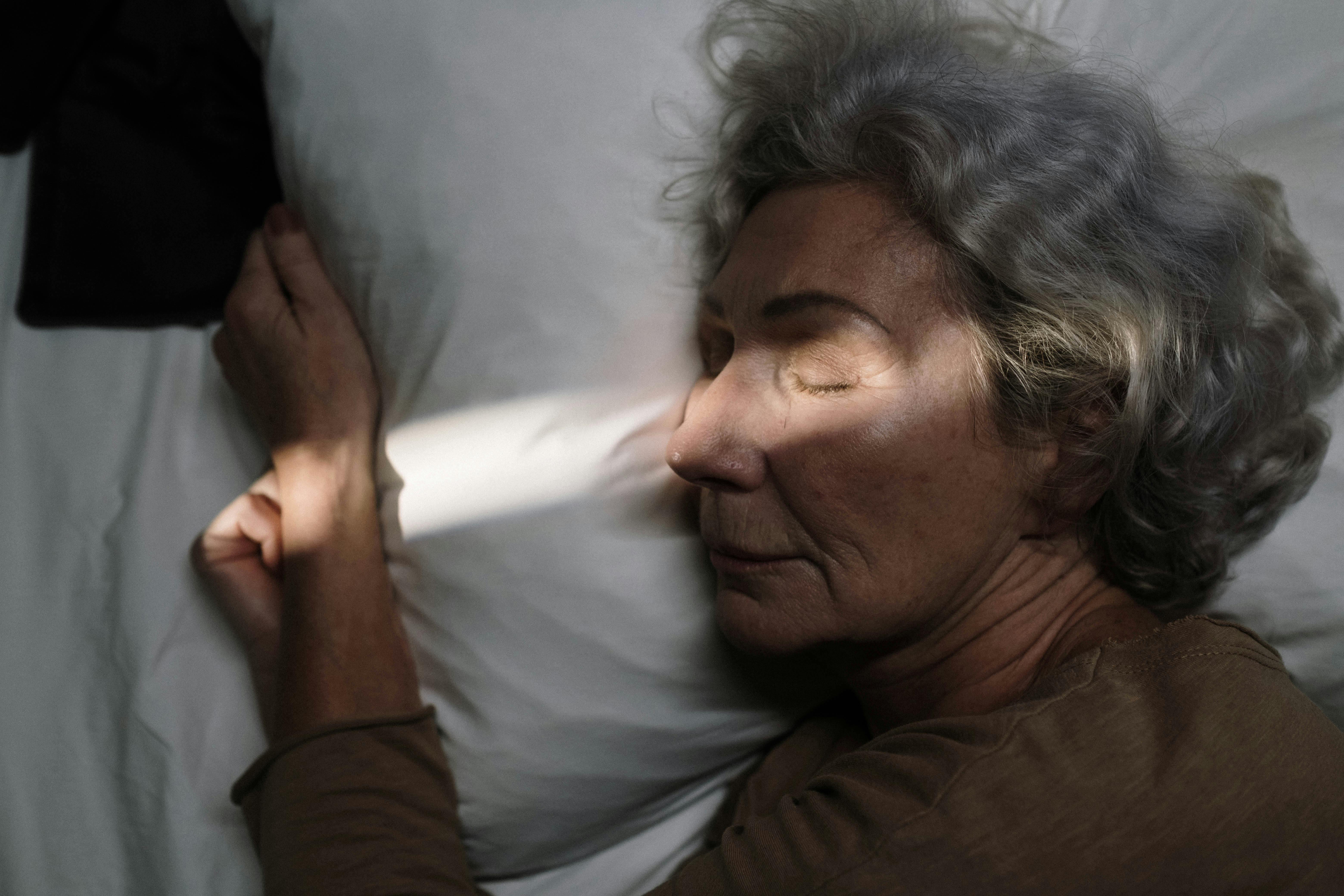 Person sleeping on a pillow with sunlight on their face.