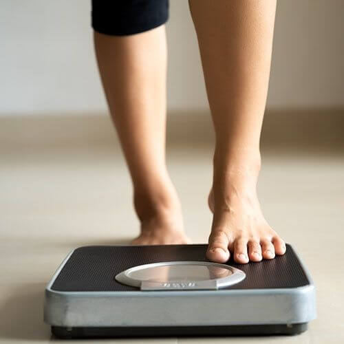 Person stepping onto a digital bathroom scale.