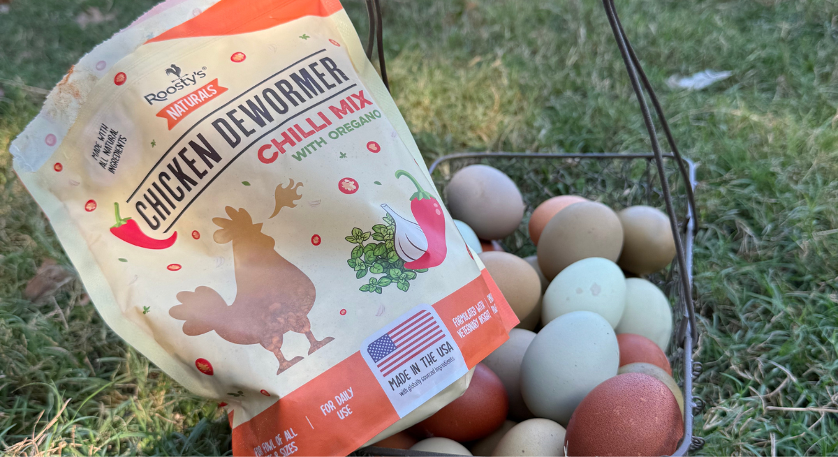 Bag of chicken dewormer and basket of eggs on grass.