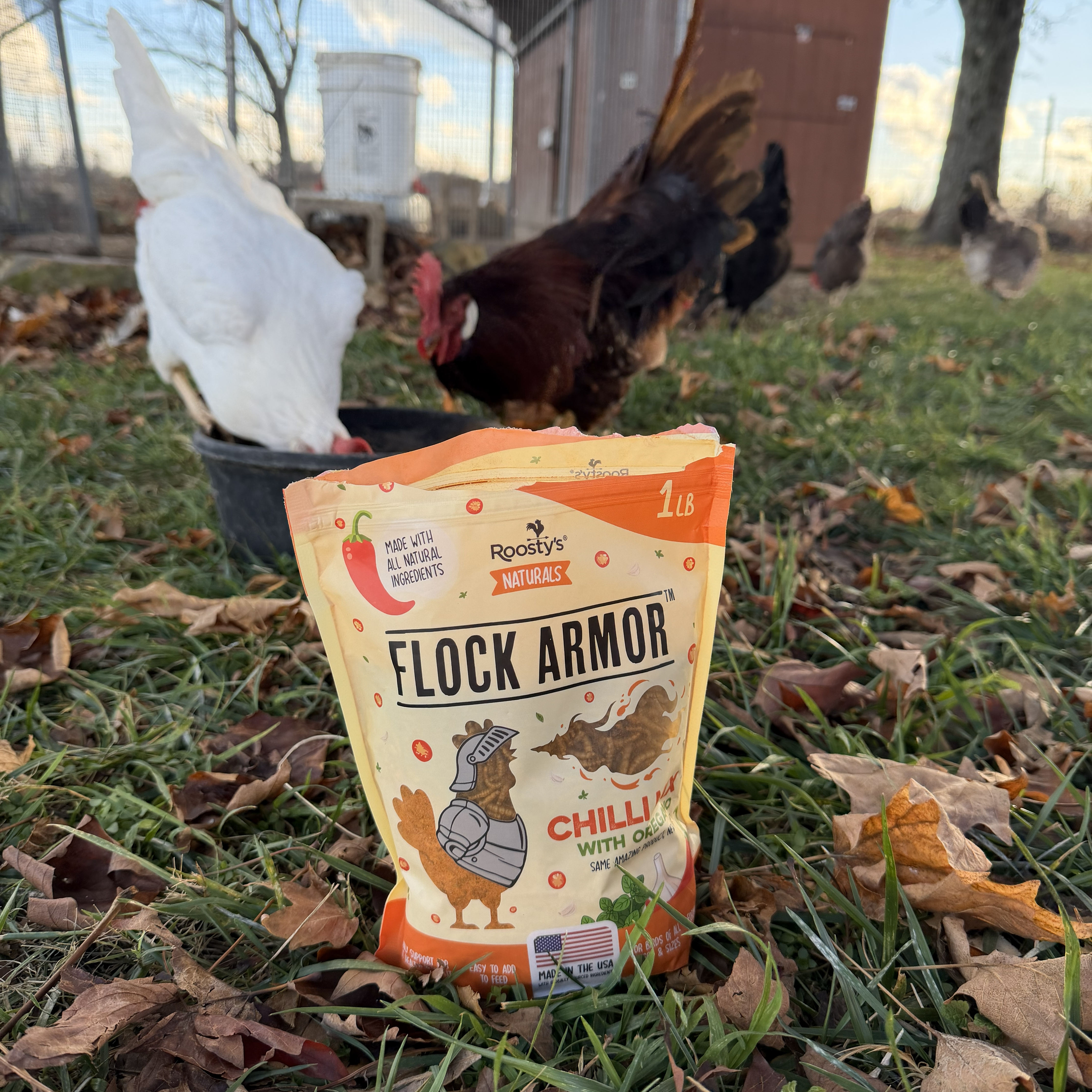 A bag labeled 'Flock Armor' on grass, with chickens in the background.
