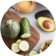 Sliced cucumber, avocado, and round zucchini on a wooden board.