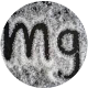 Black 'Mg' letters on a textured gray circular background.