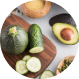 Sliced cucumber, avocado, and round zucchini on a wooden board.