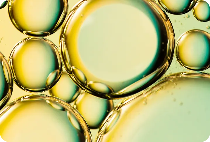 A close-up, abstract photograph of yellow and green oil bubbles.