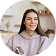 Smiling woman holding a small object, in a kitchen setting.