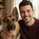 A smiling man with his arm around a German Shepherd dog, both looking at the camera.