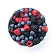An overhead shot of a light blue bowl filled with raspberries, blueberries, and blackberries on a white background.