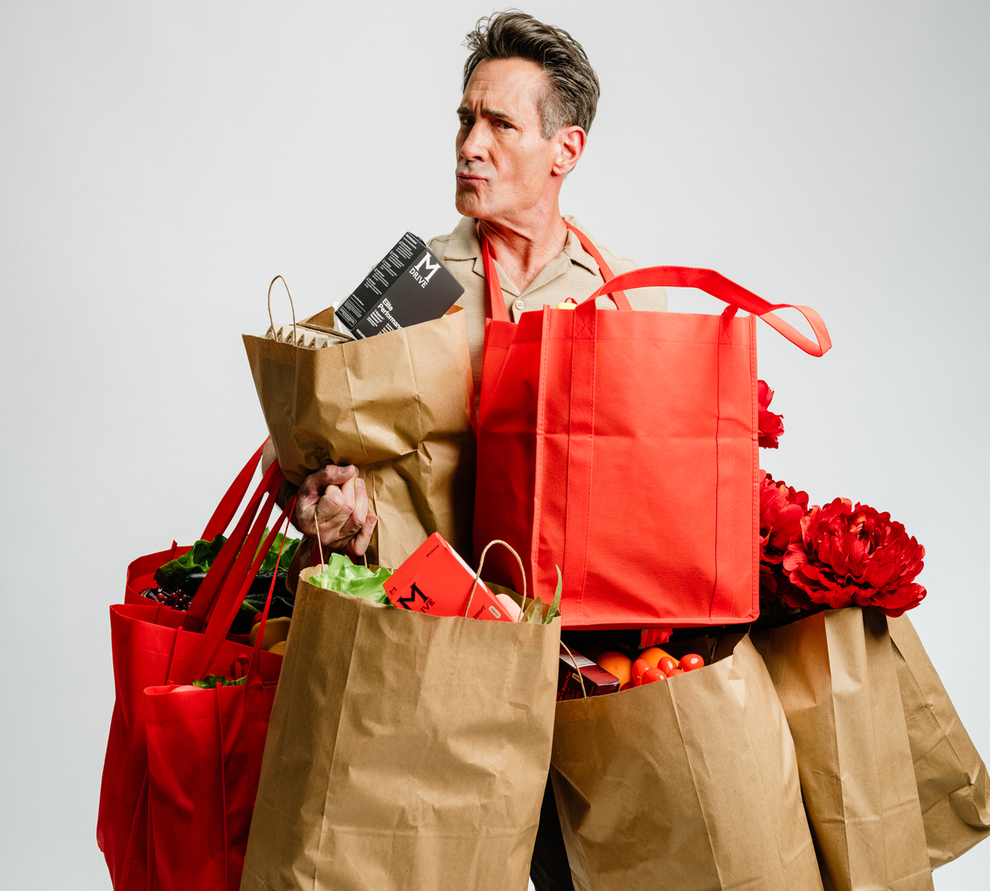 Person holding multiple grocery bags filled with various items.