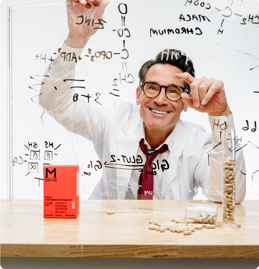 Man writing on glass board with chemical formulas, pills on table.