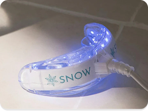 A glowing LED mouthpiece labeled 'SNOW' on a tiled surface.