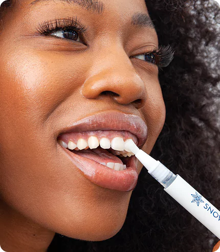 Person using a teeth whitening pen on their teeth.