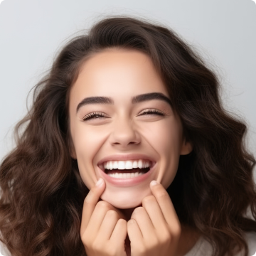 A person with curly hair laughs joyfully, showing bright teeth.