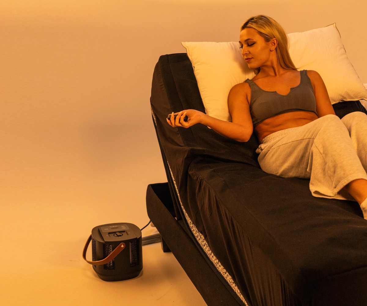Woman relaxing on an adjustable bed with a remote control.
