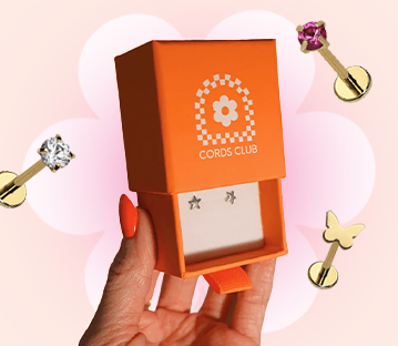 Orange jewelry box with star earrings, surrounded by decorative pins.