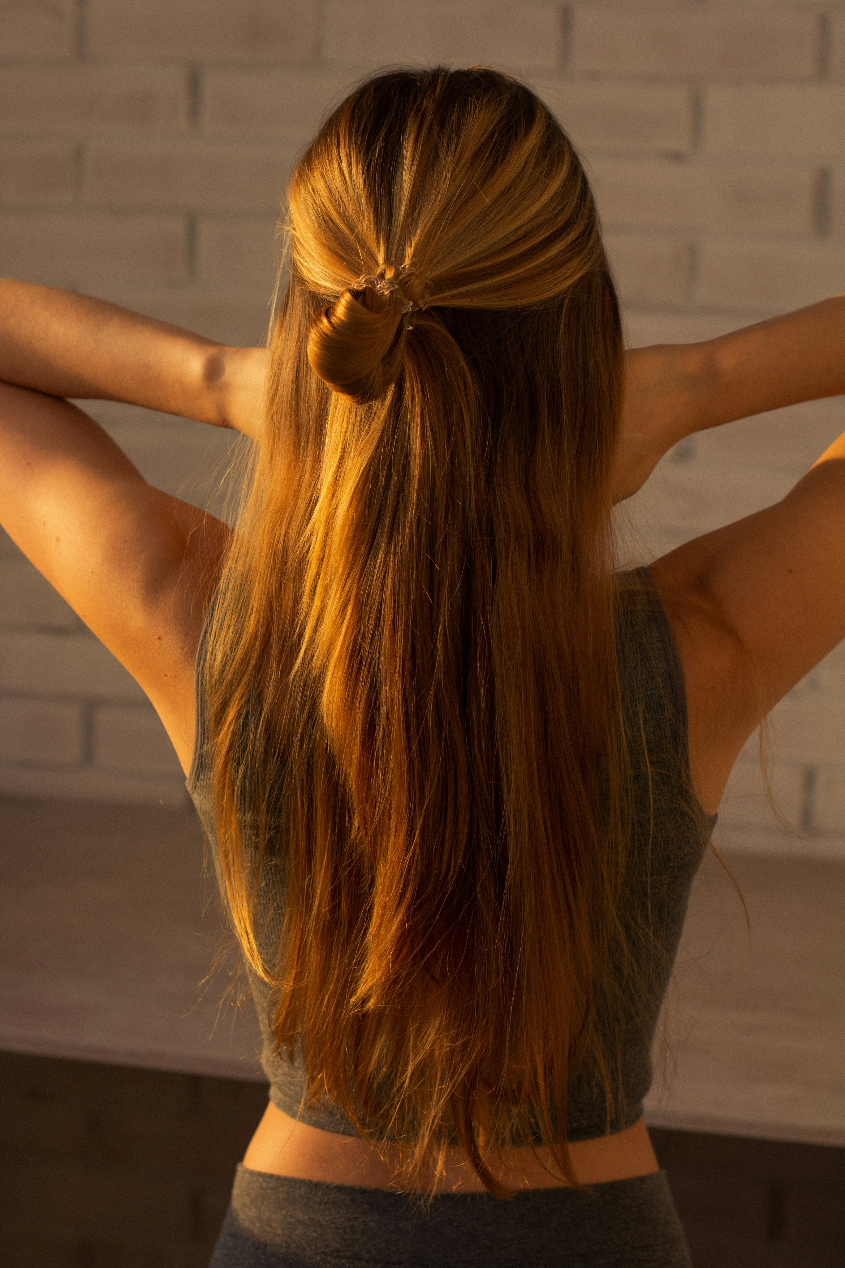 A woman with long, reddish-blonde hair in a half-up bun, seen from behind.