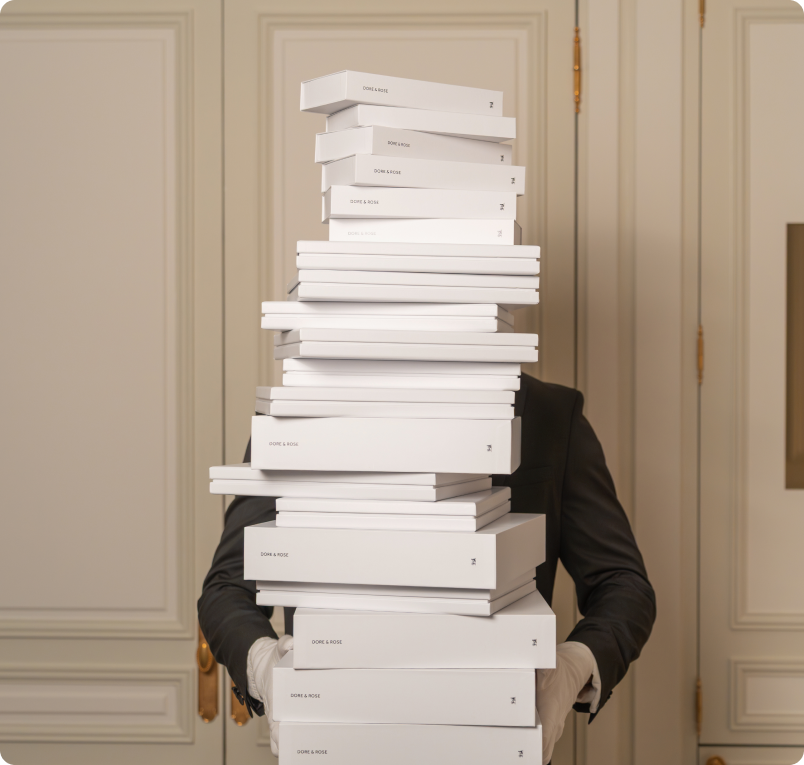 Person holding a tall stack of white boxes in front of a door.