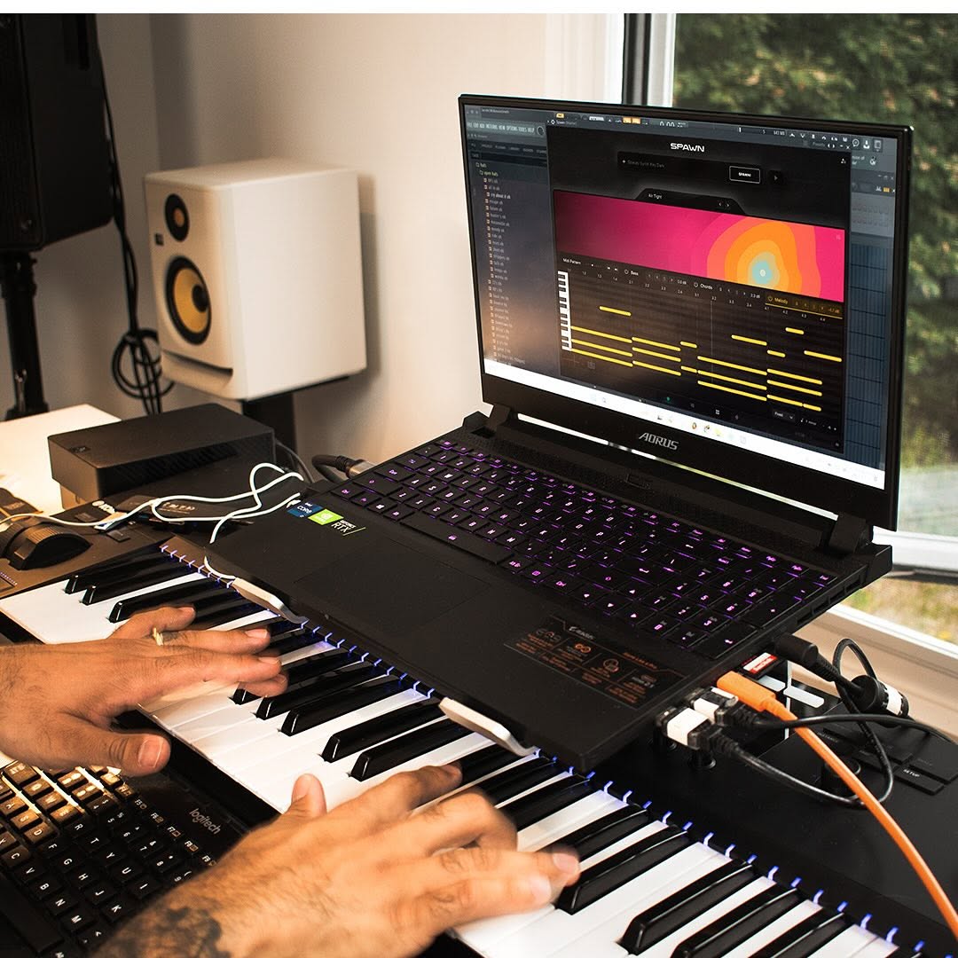 Hands playing a keyboard with a laptop displaying music software.