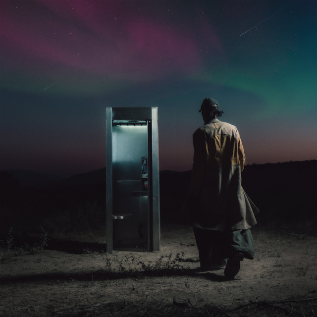 Person walking towards a phone booth under a colorful night sky.