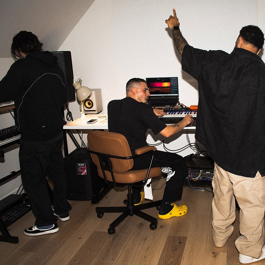 Three people in a music studio with keyboards and a computer.