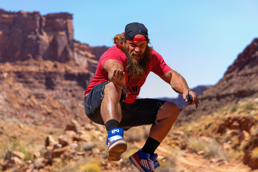 Man jumping energetically in a desert landscape with rocky formations.
