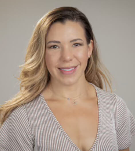 A woman smiling in a striped V-neck top against a neutral background.