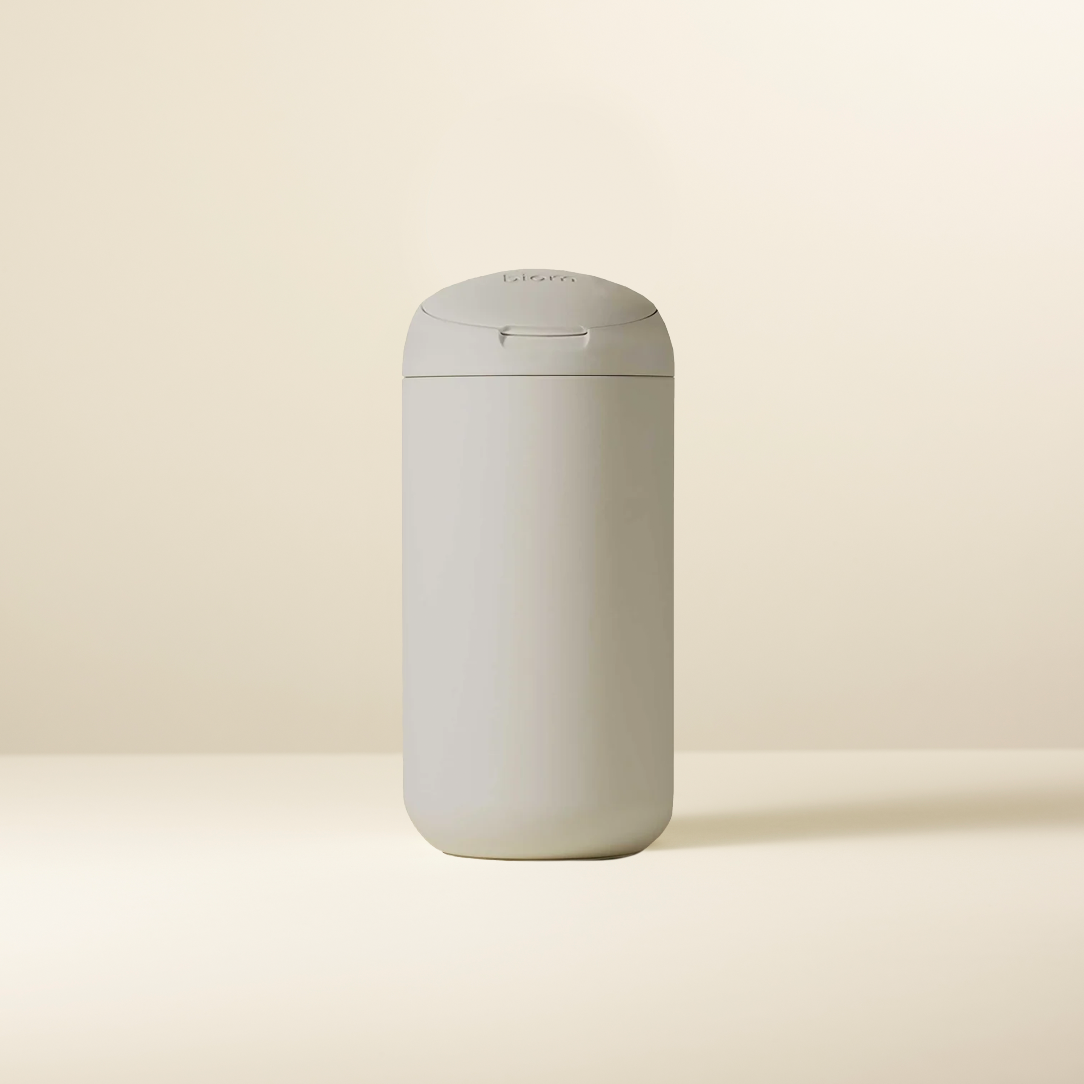Beige cylindrical container with a rounded lid on a neutral background.