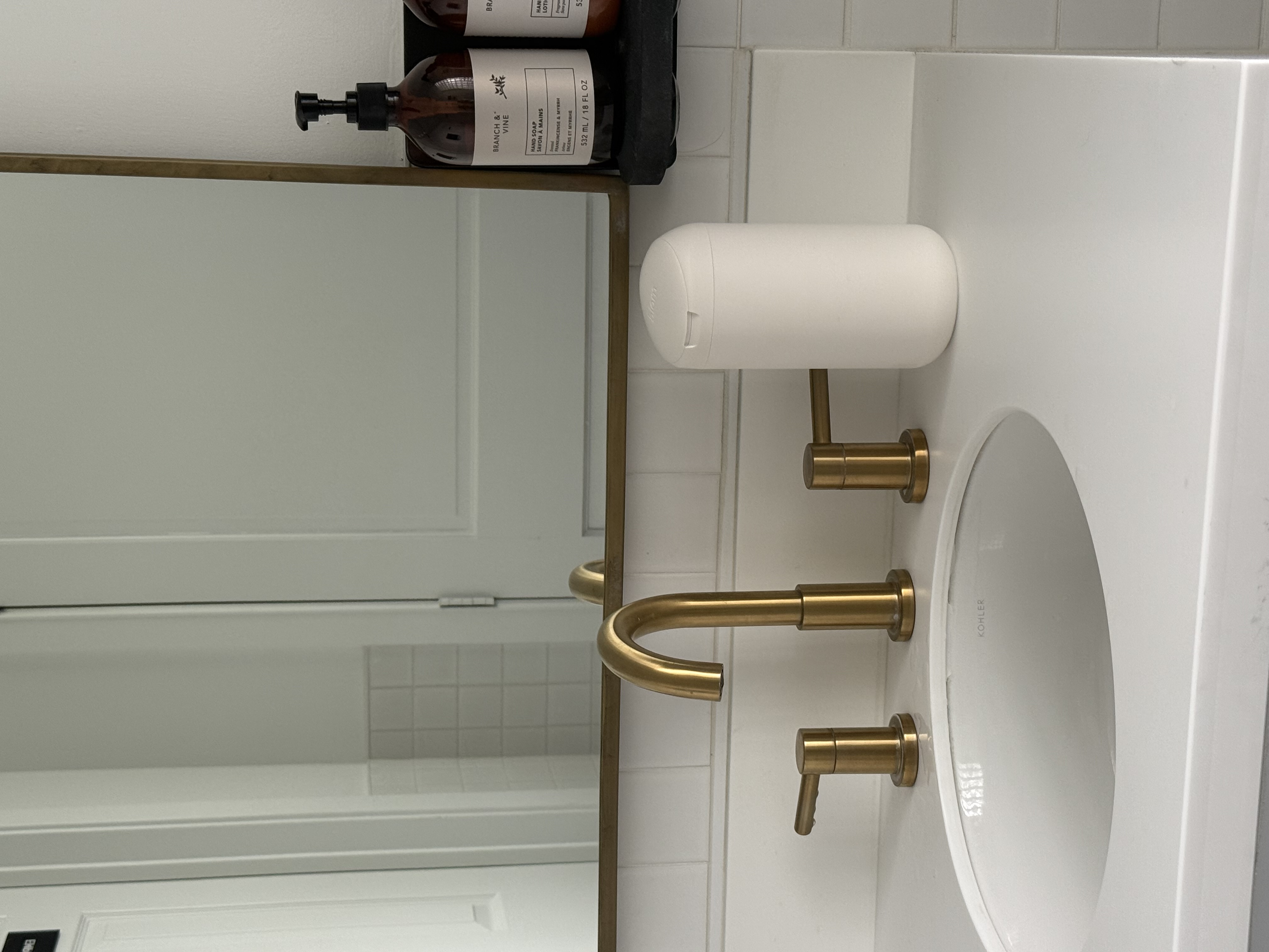Bathroom sink with gold faucet and soap dispensers.