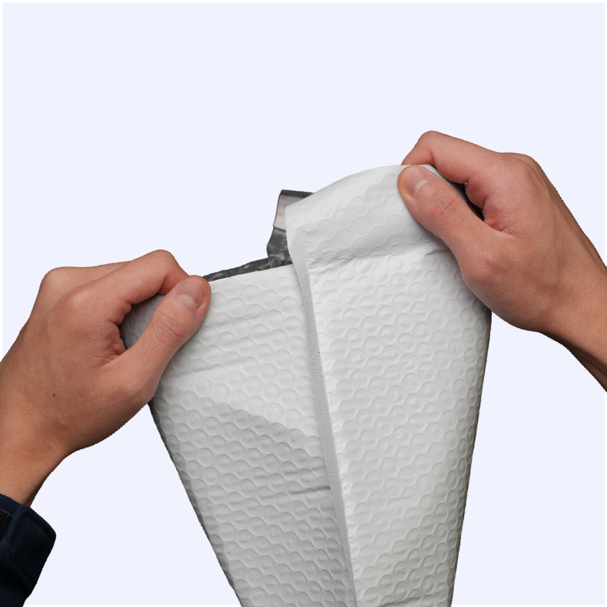 A person's hands opening a white padded bubble mailer against a plain background.