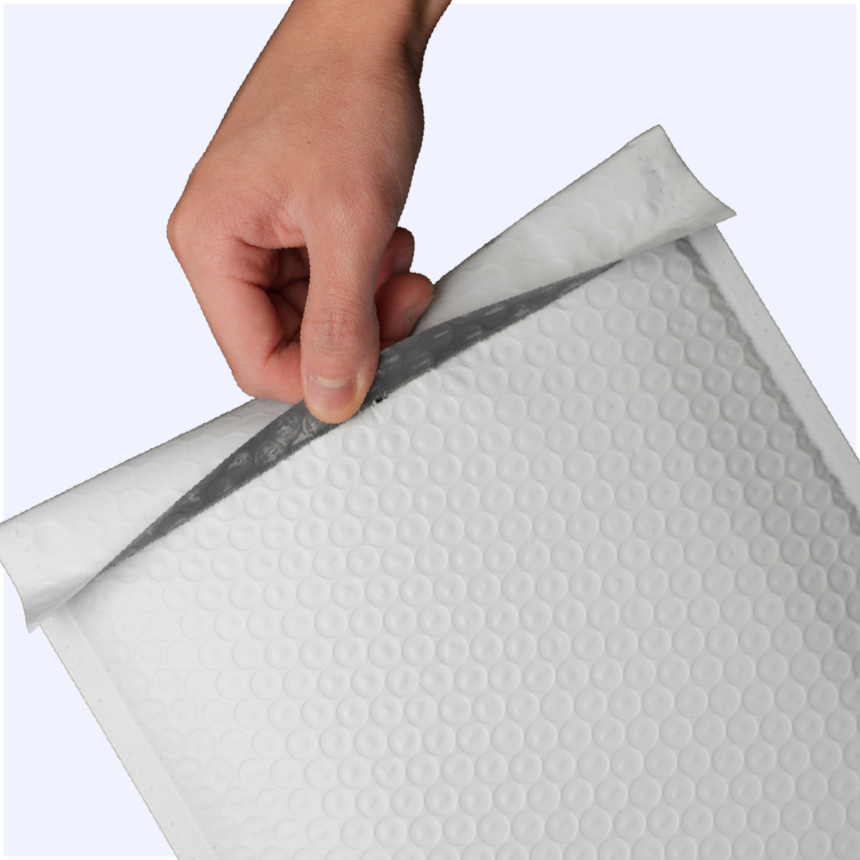 A hand peels back the adhesive strip cover on a white bubble mailer against a white background.
