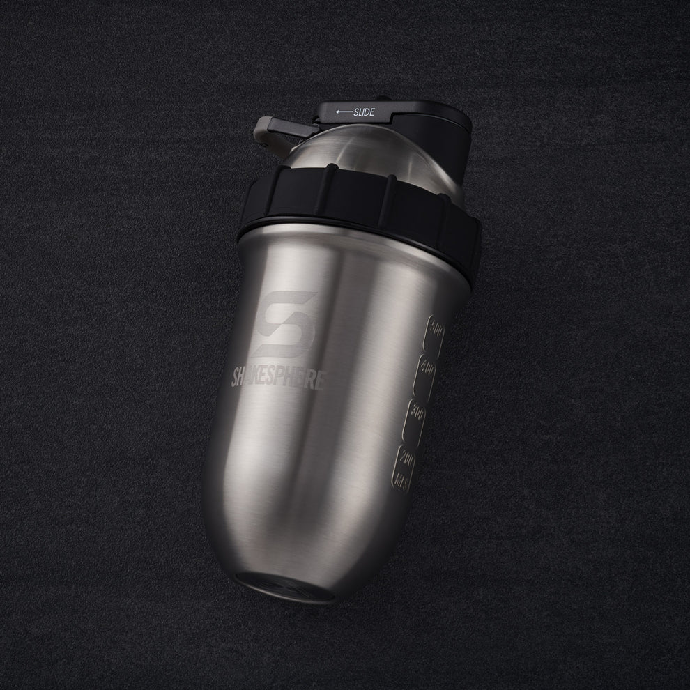 Stainless steel shaker bottle with measurement markings and a black lid on a dark background.