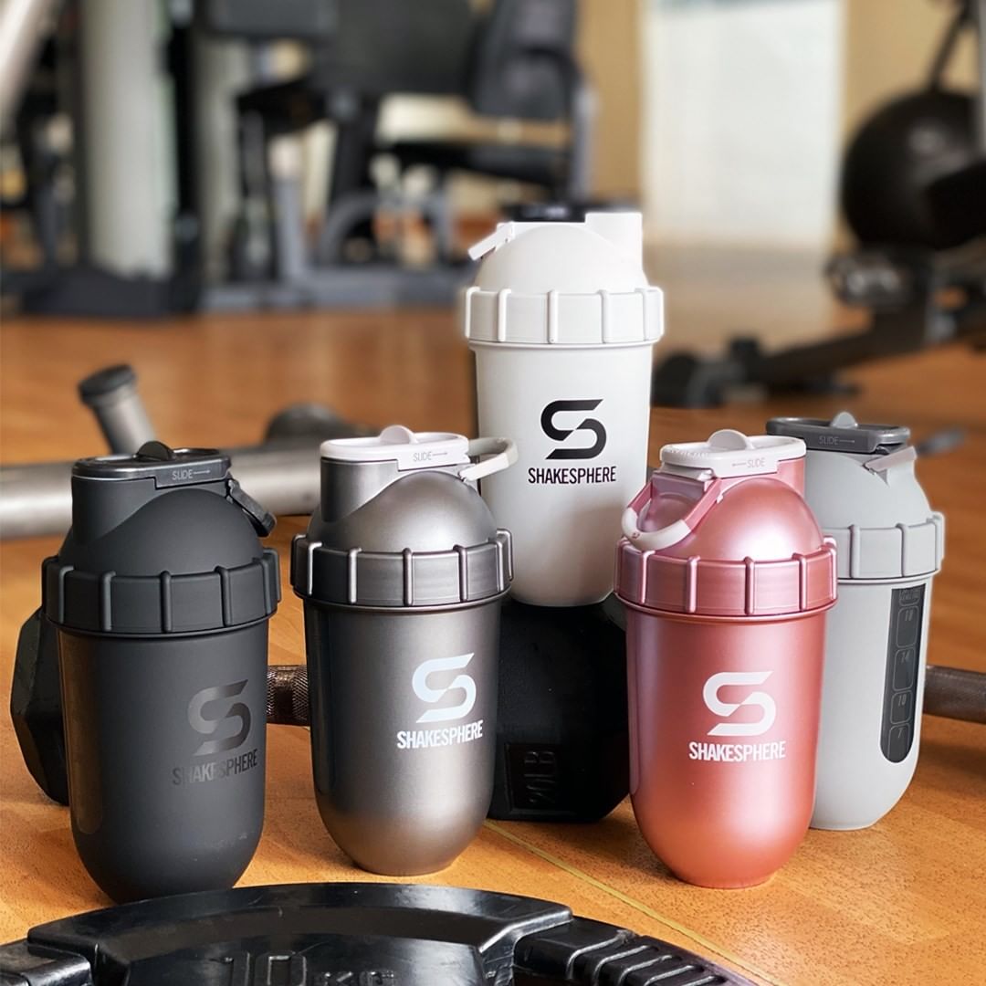 Five Shakesphere shaker bottles in various colors on a gym floor.