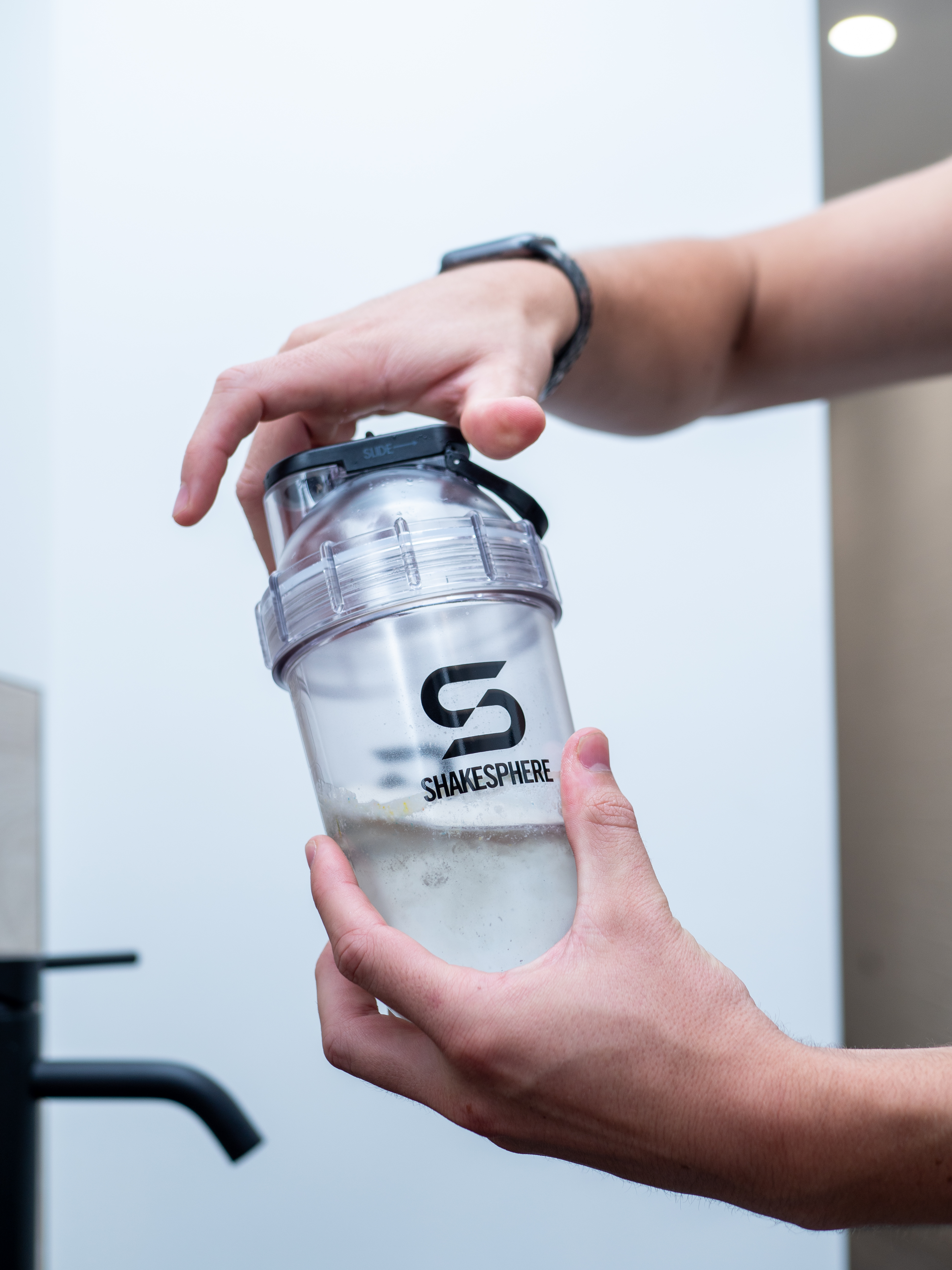 Person holding a Shakesphere shaker bottle with ice and liquid inside.