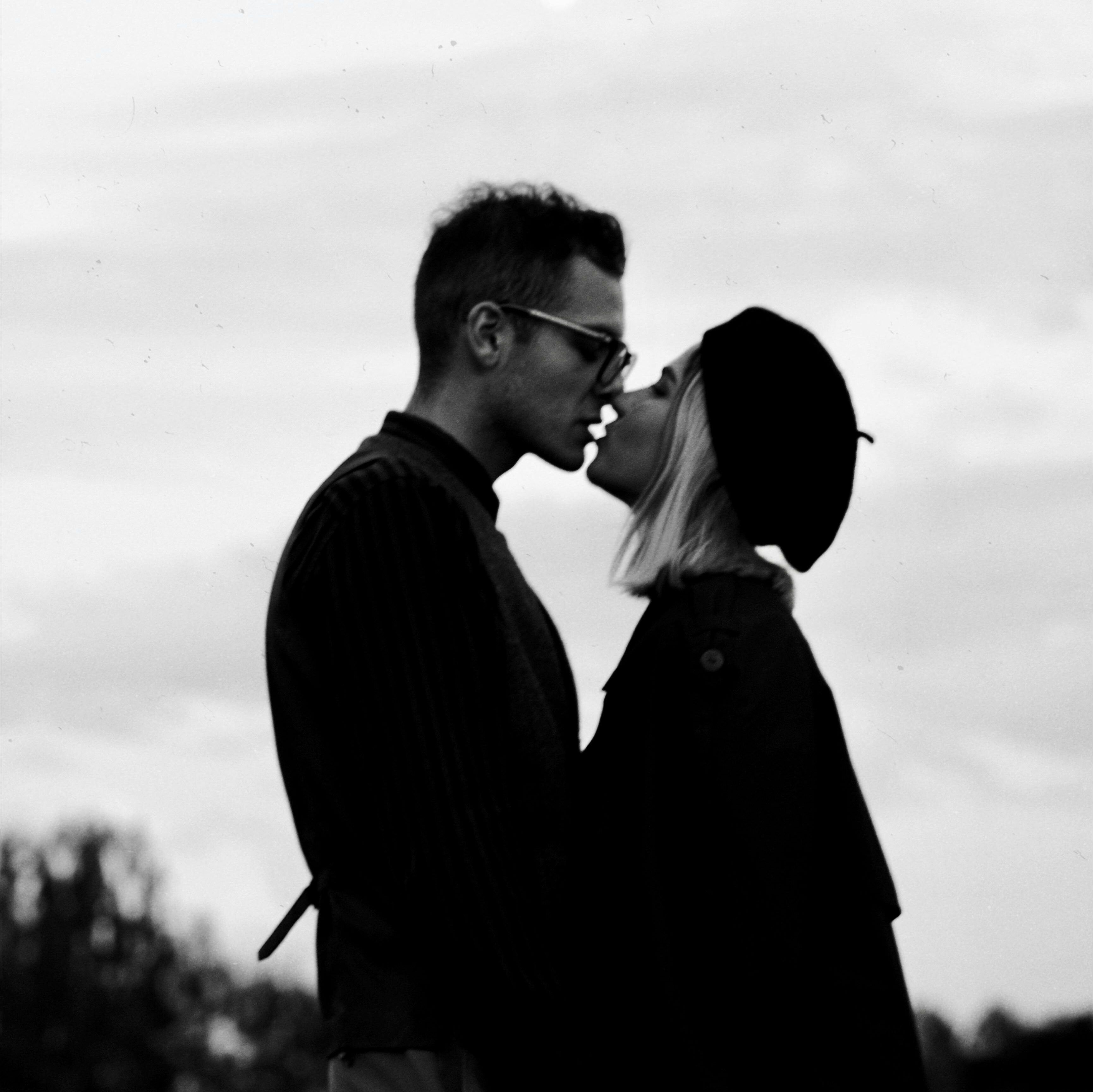 Black and white photo of a couple about to kiss outdoors.