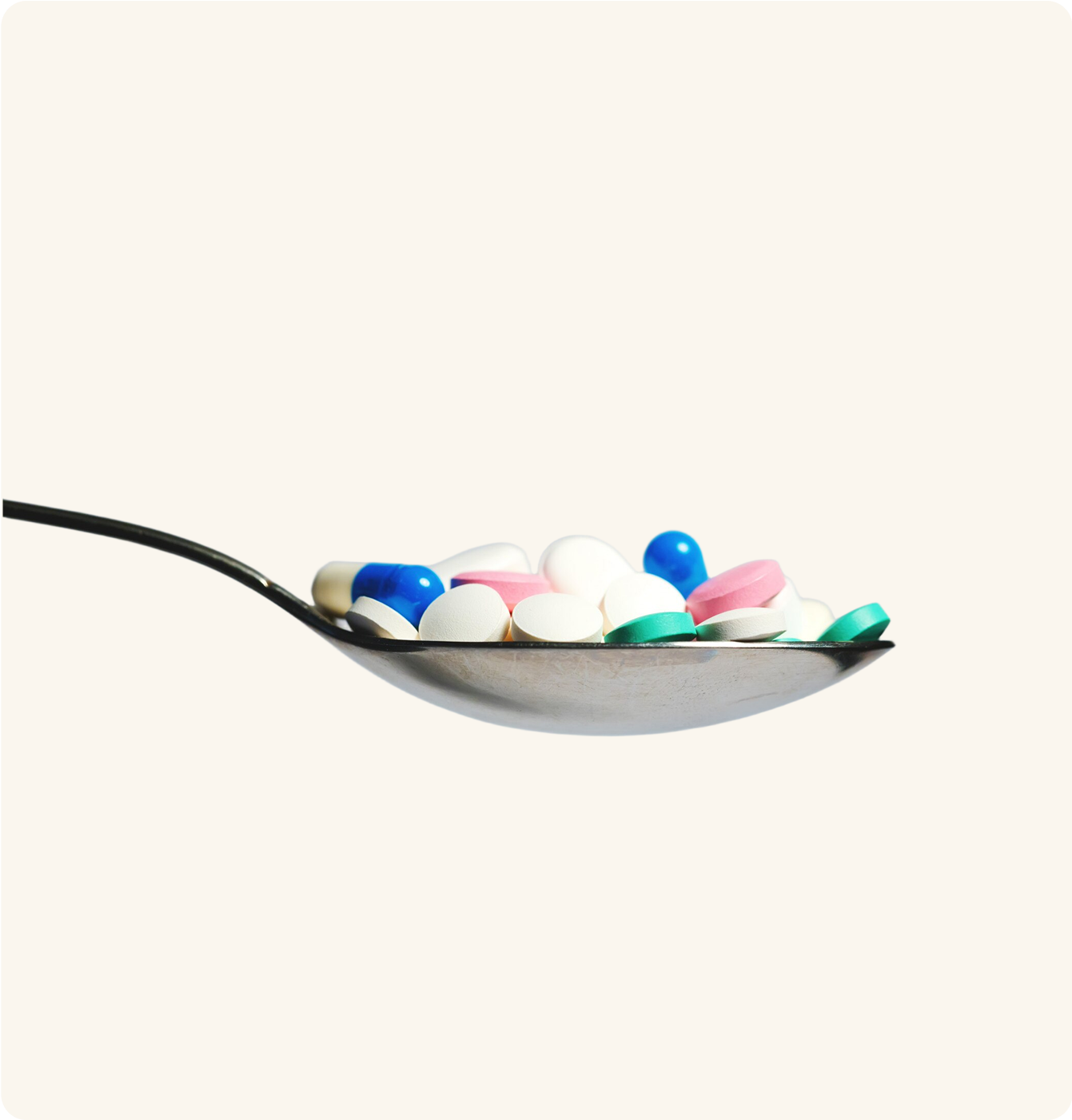 A spoon filled with various colorful pills.