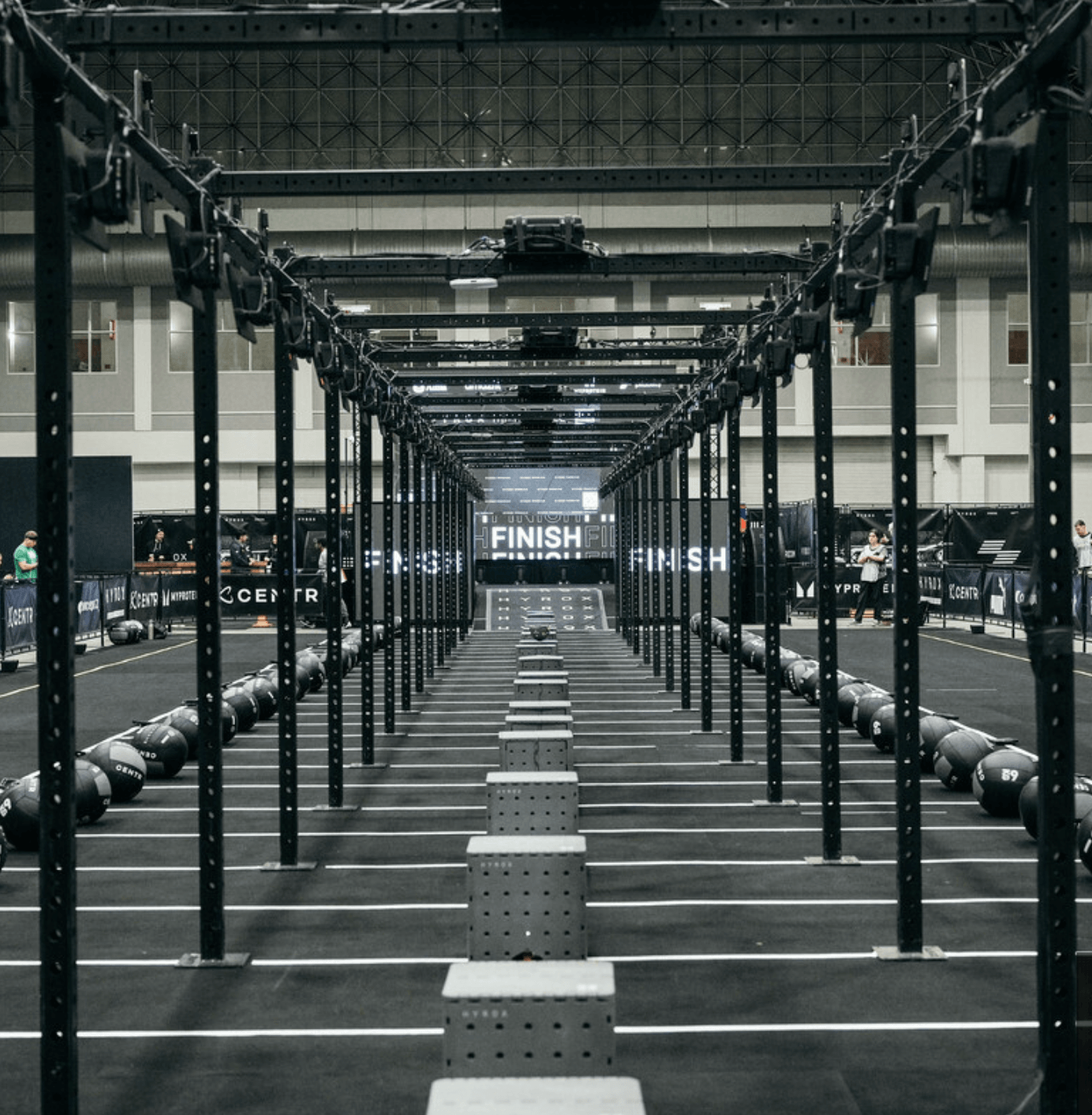 A black and white photograph of an empty indoor fitness competition course with lanes of equipment.