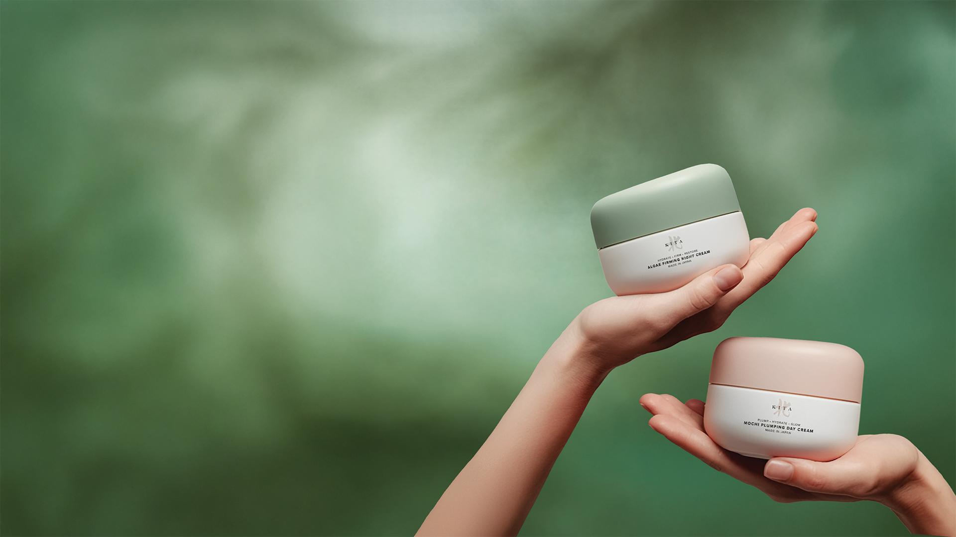 Two hands holding skincare cream jars with green background.