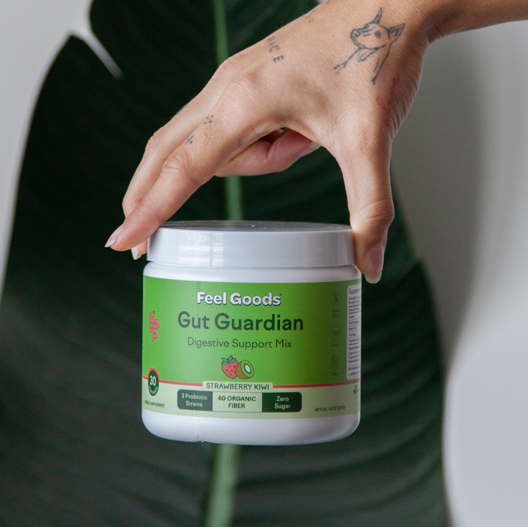 Hand holding a container of Gut Guardian digestive support mix.