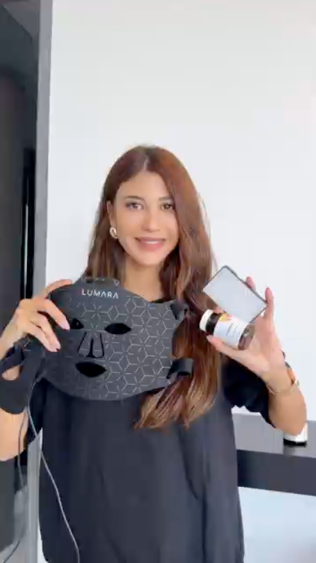 Person holding a black face mask and a small bottle.