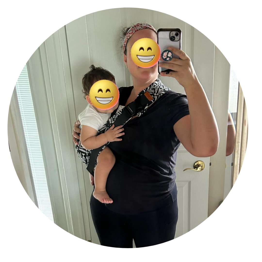 Person taking a mirror selfie holding a baby in a carrier.