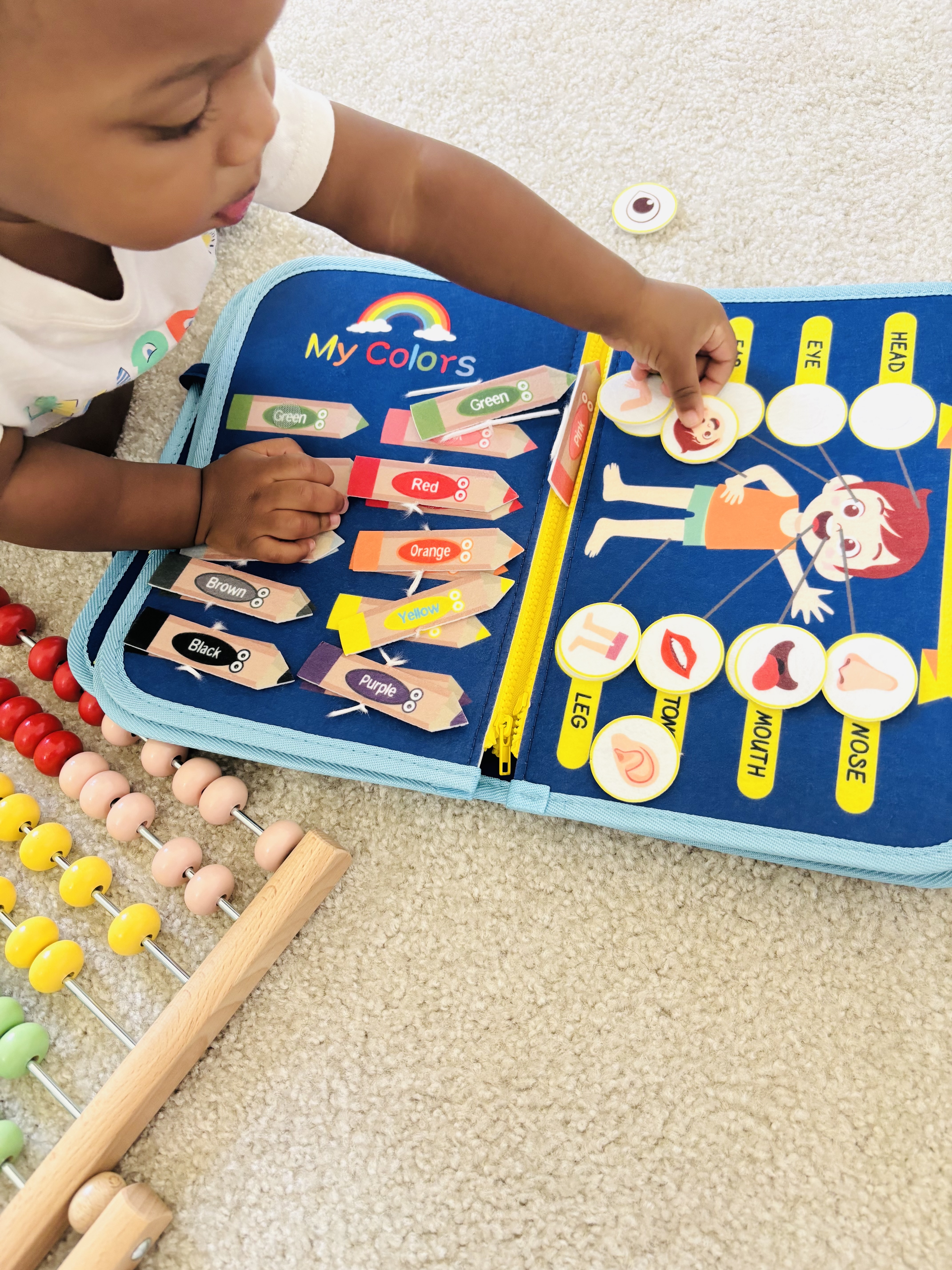 Child playing with a colorful educational book and abacus on the floor.
