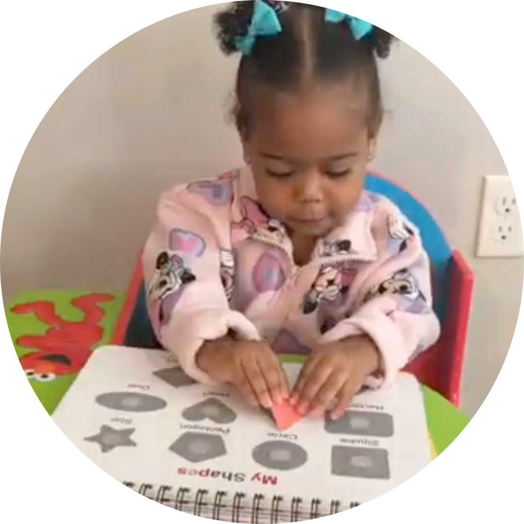 A toddler sits with a 'My Colors' book, matching a purple crayon-shaped piece to the page.