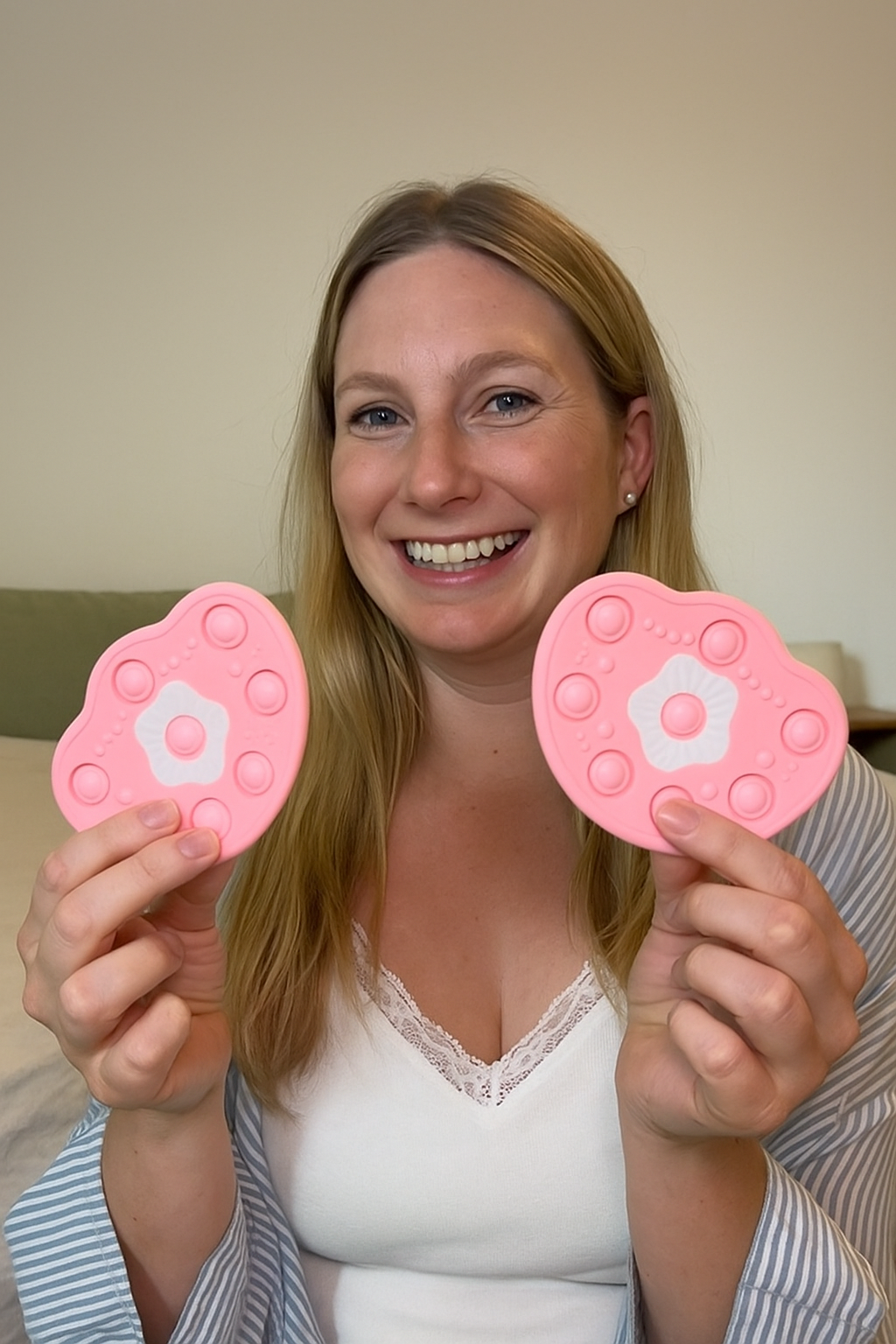 Person smiling, holding two pink silicone items with circular patterns.