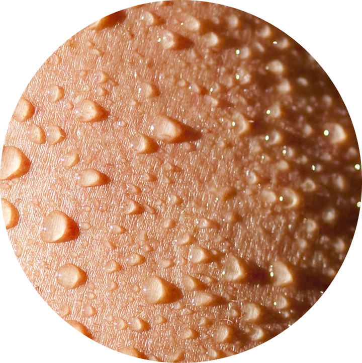 A close-up, circular photograph of water droplets beading on human skin.