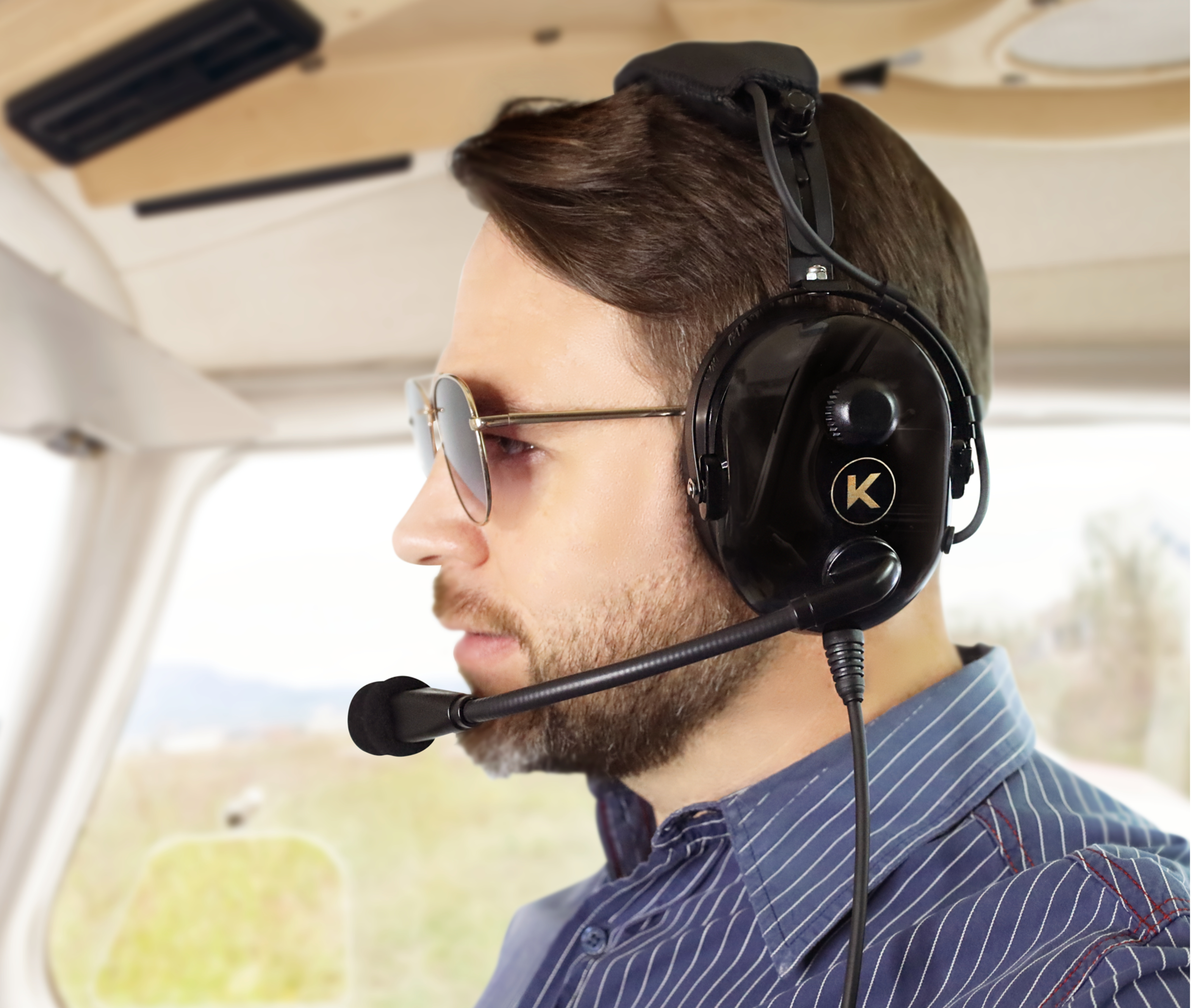 Man wearing a headset and sunglasses inside an aircraft cockpit.