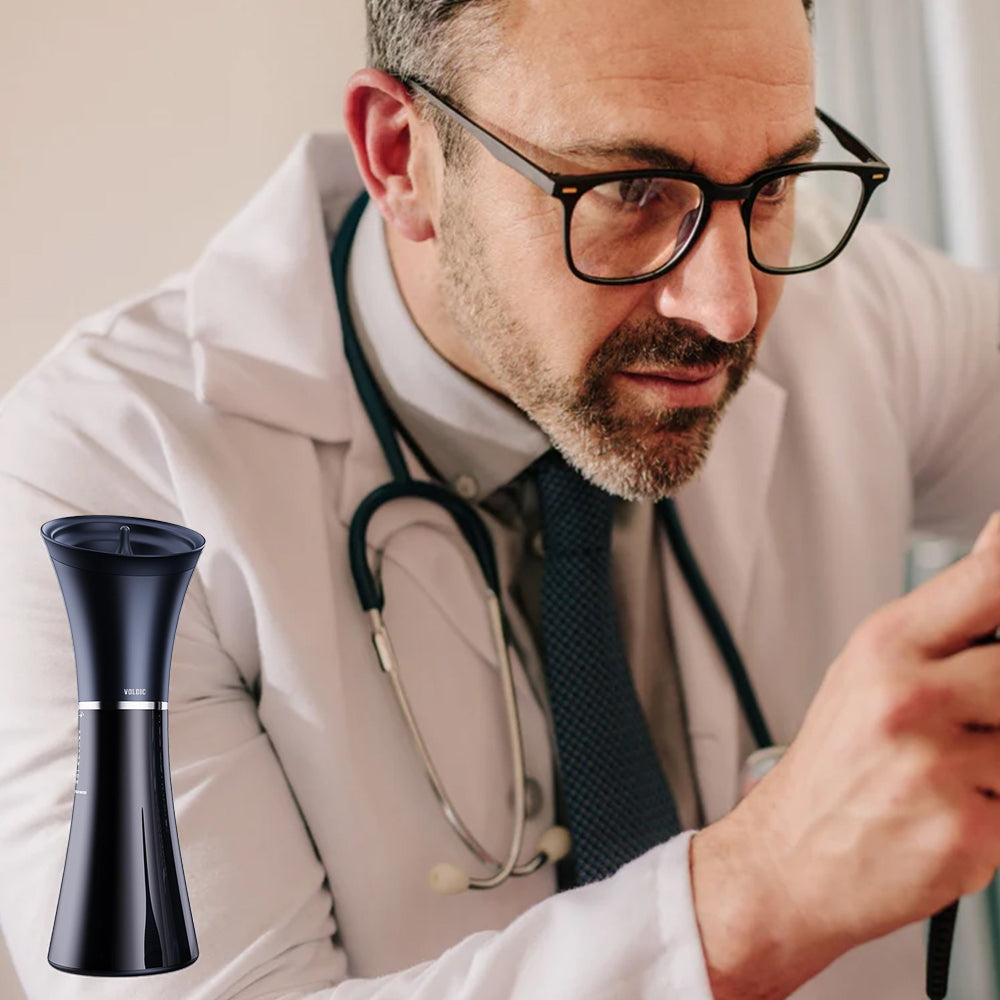 A doctor in a white coat and glasses, with a black, vase-shaped electronic device in the foreground.