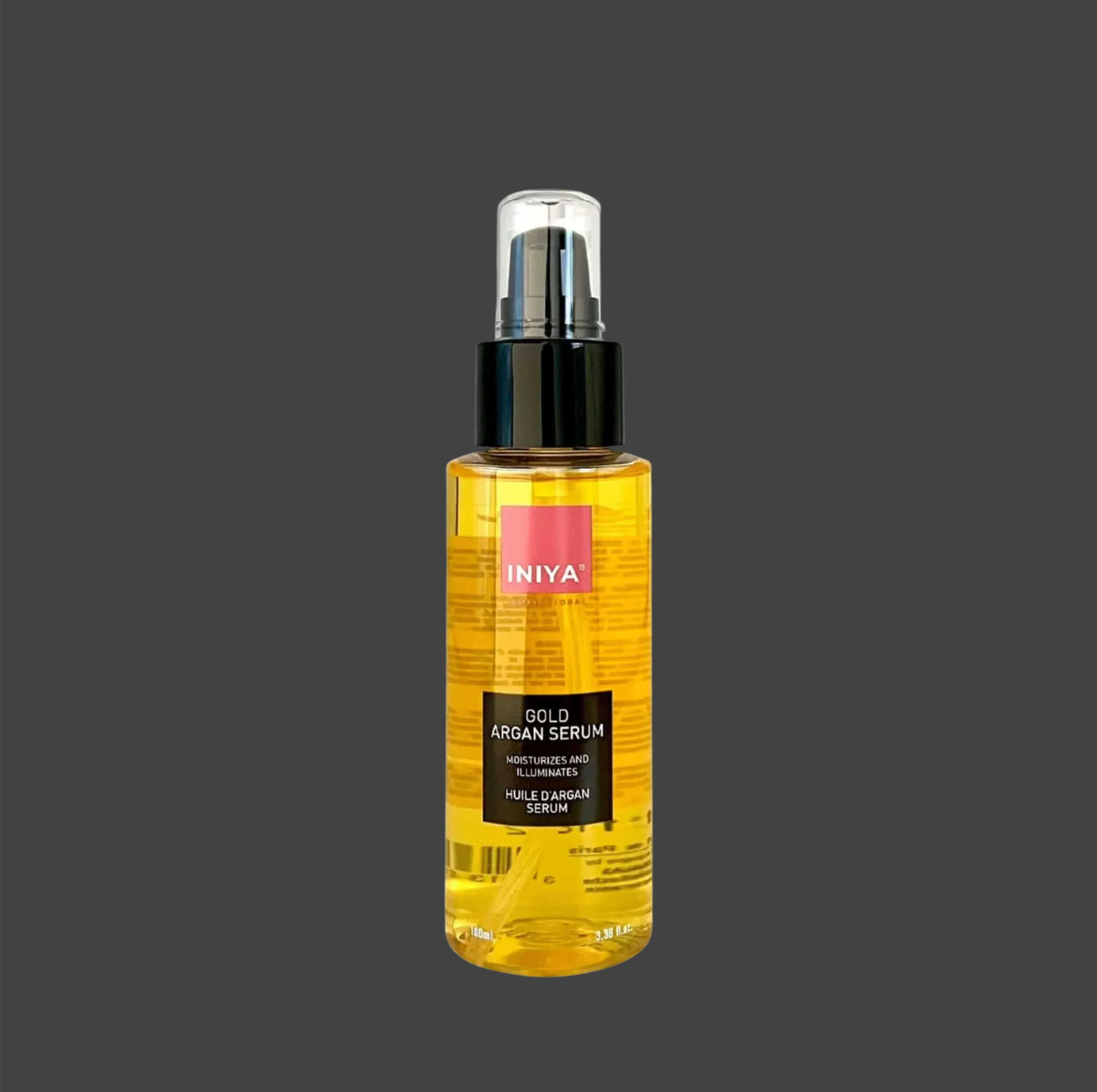 A bottle of INIYA Gold Argan Serum with a black pump cap.