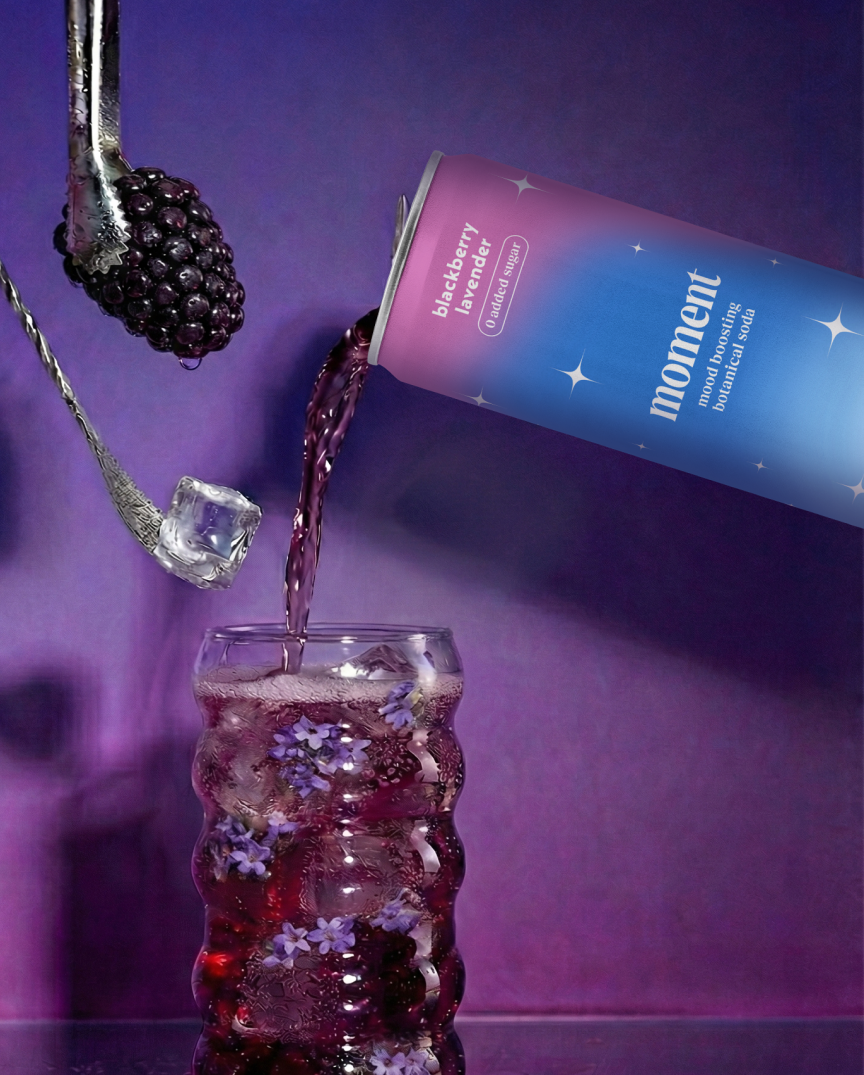 A can pours purple liquid into a glass with flowers and ice.